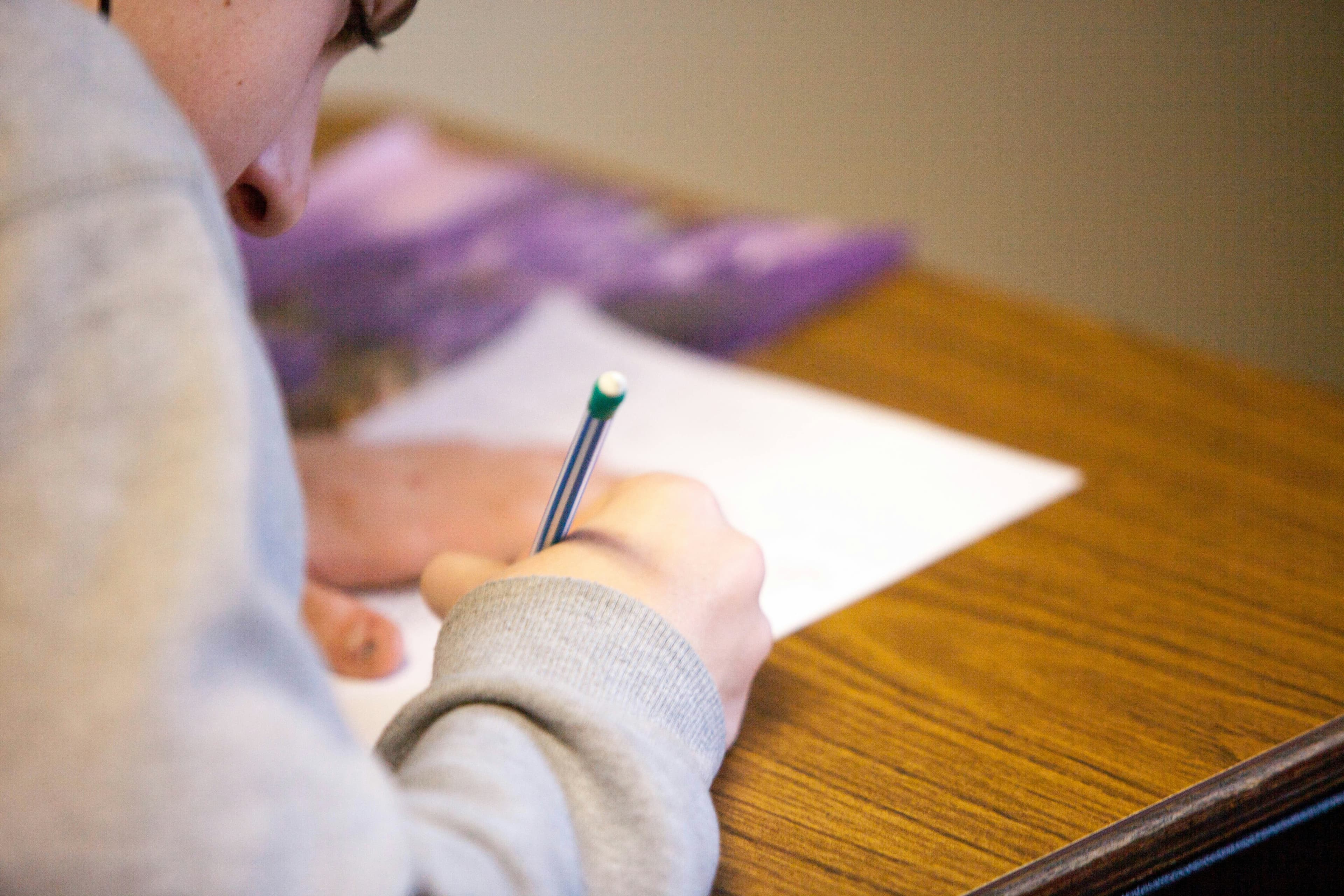 A person writing with a pencil