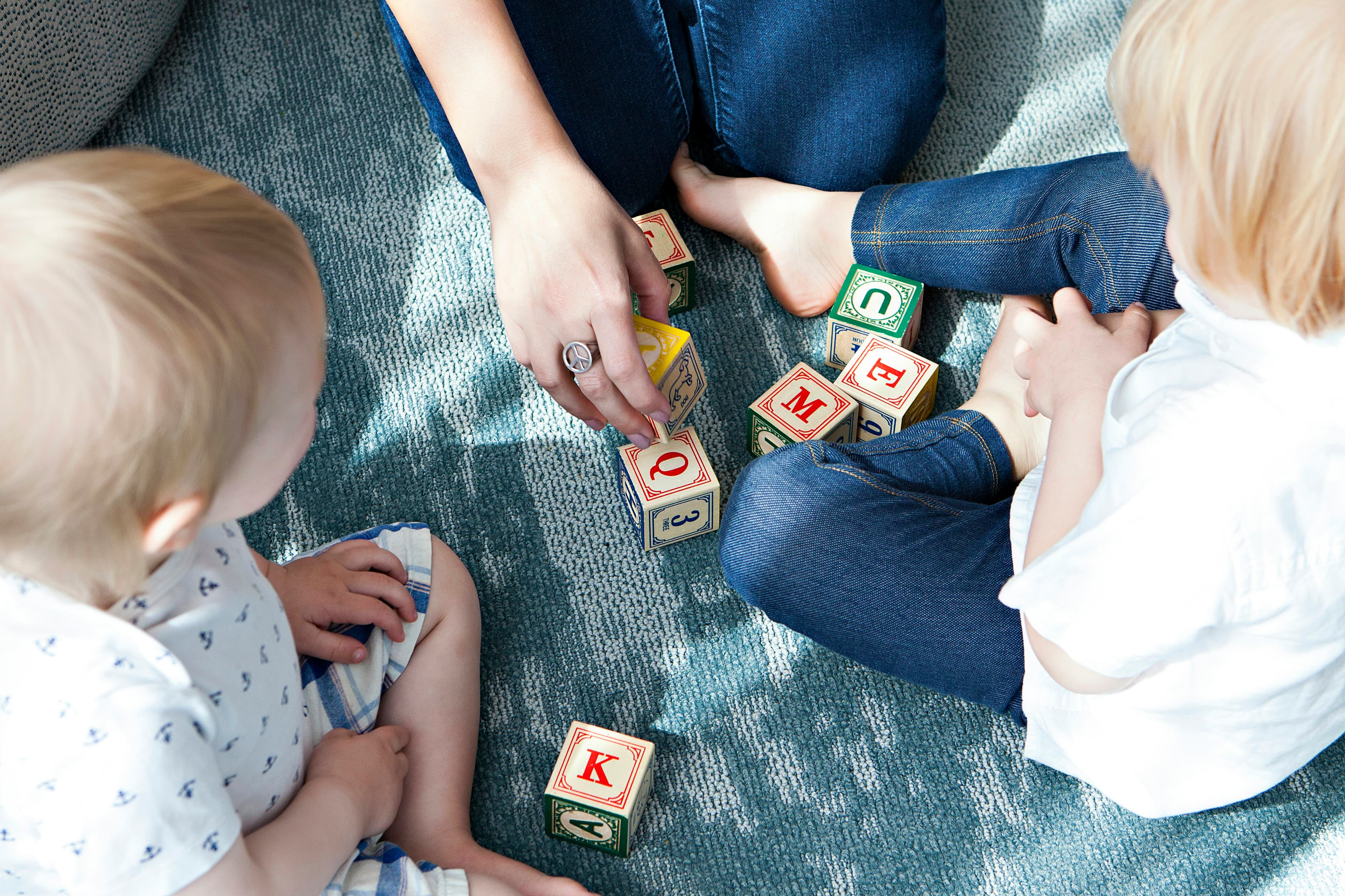 Two toddlers playing with colorful letter blocks