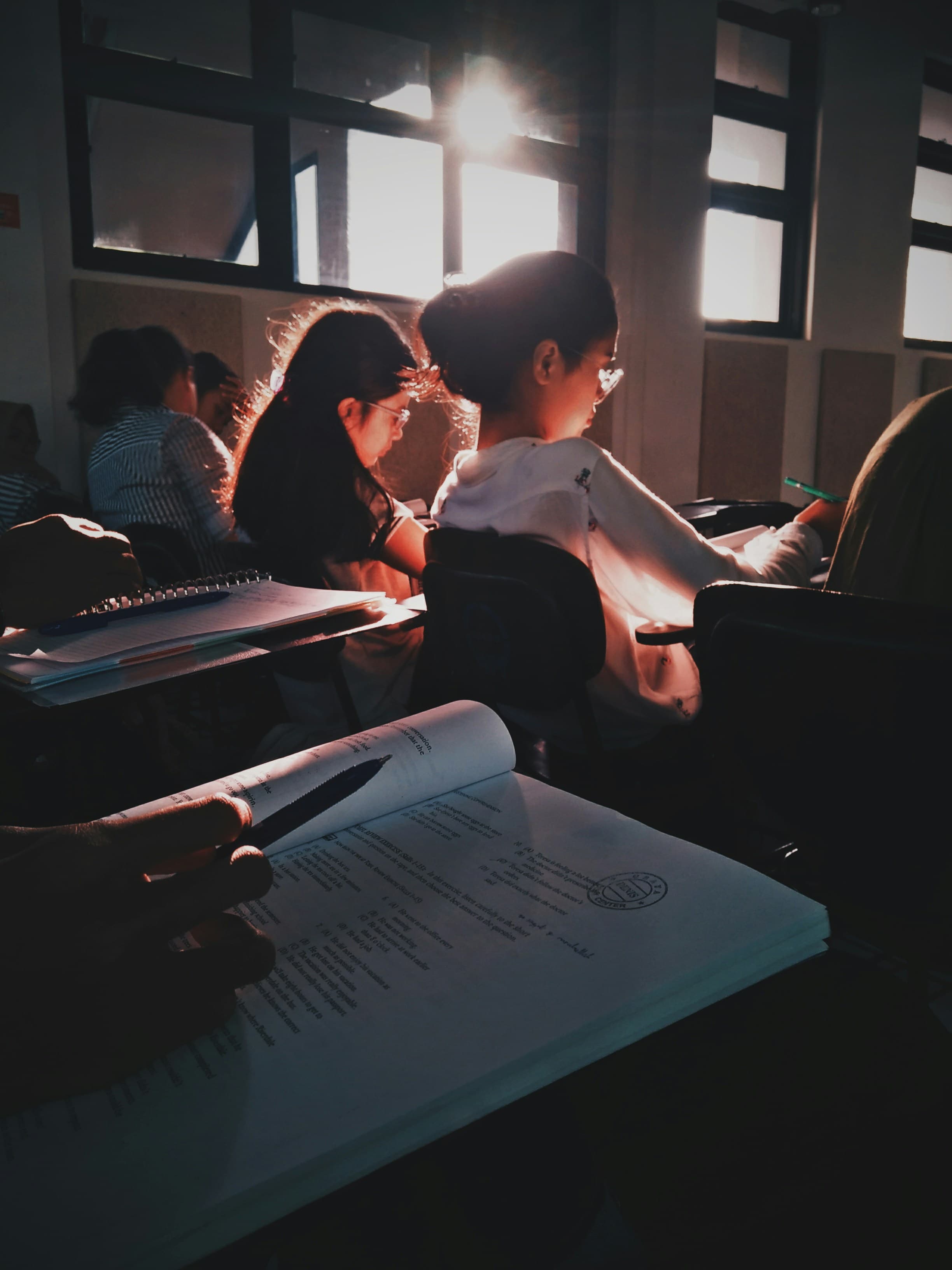 Students in a sunlit classroom reading textbooks at their desks