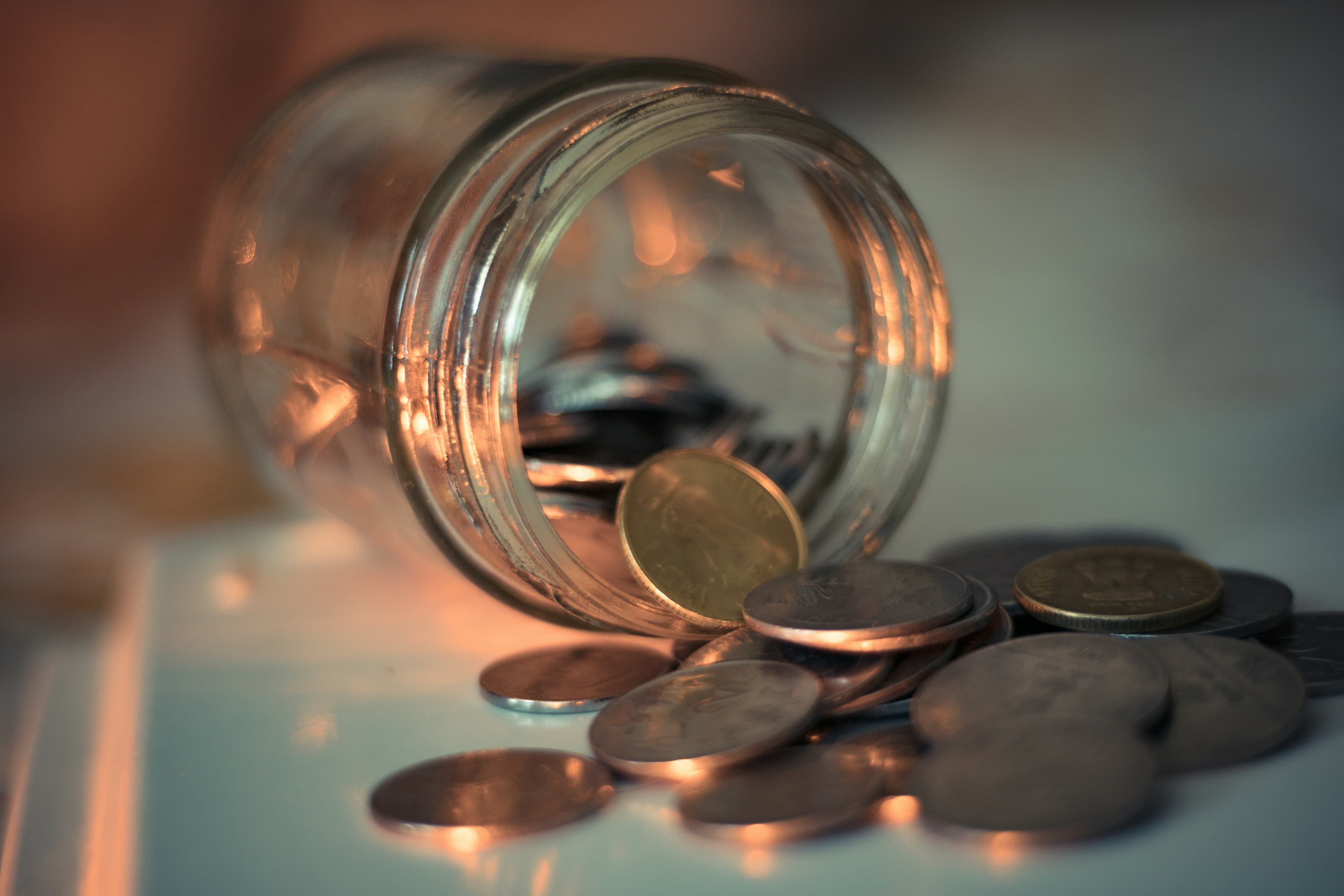A clear glass jar filled with coins