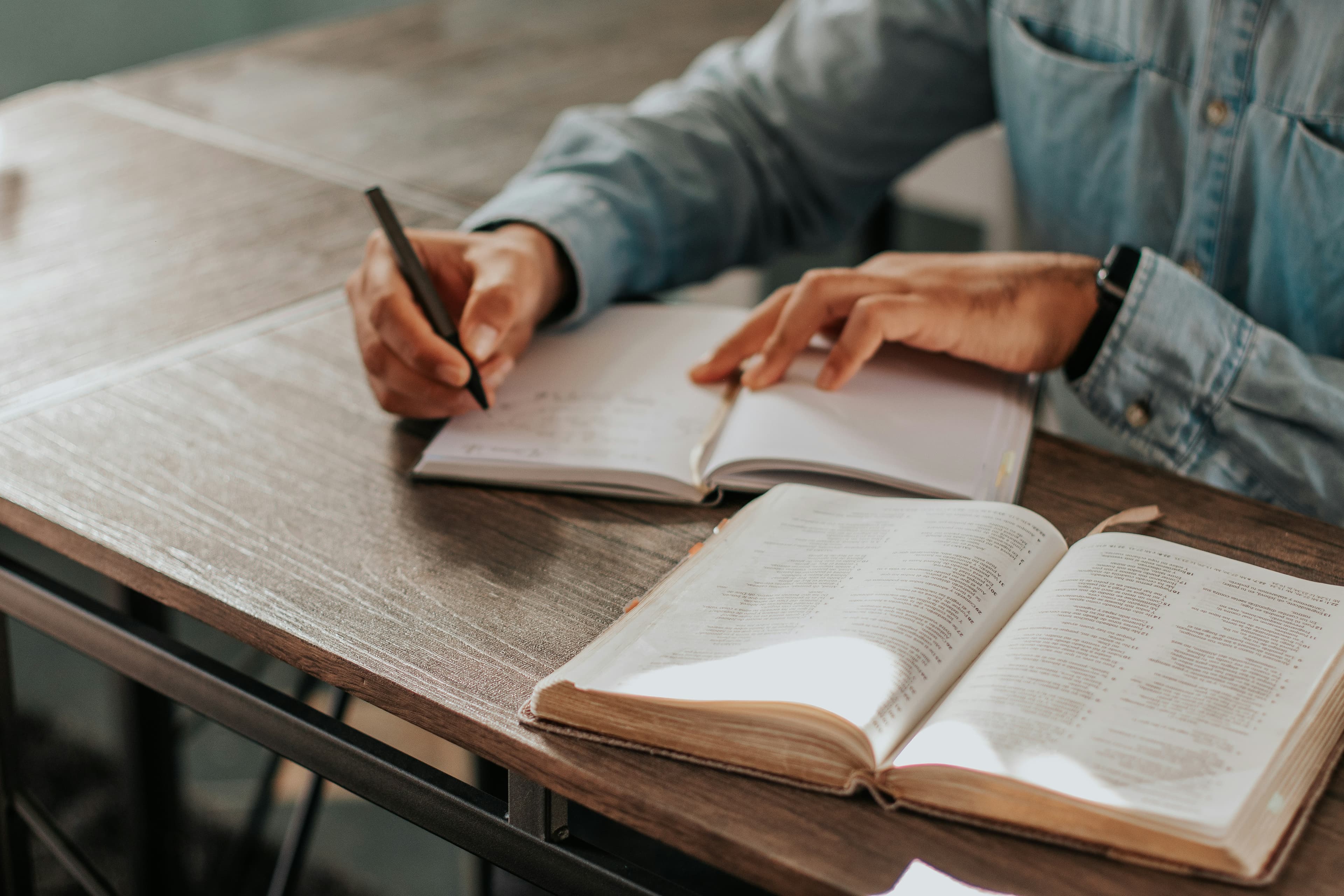 A person holding a pen and writing on white paper