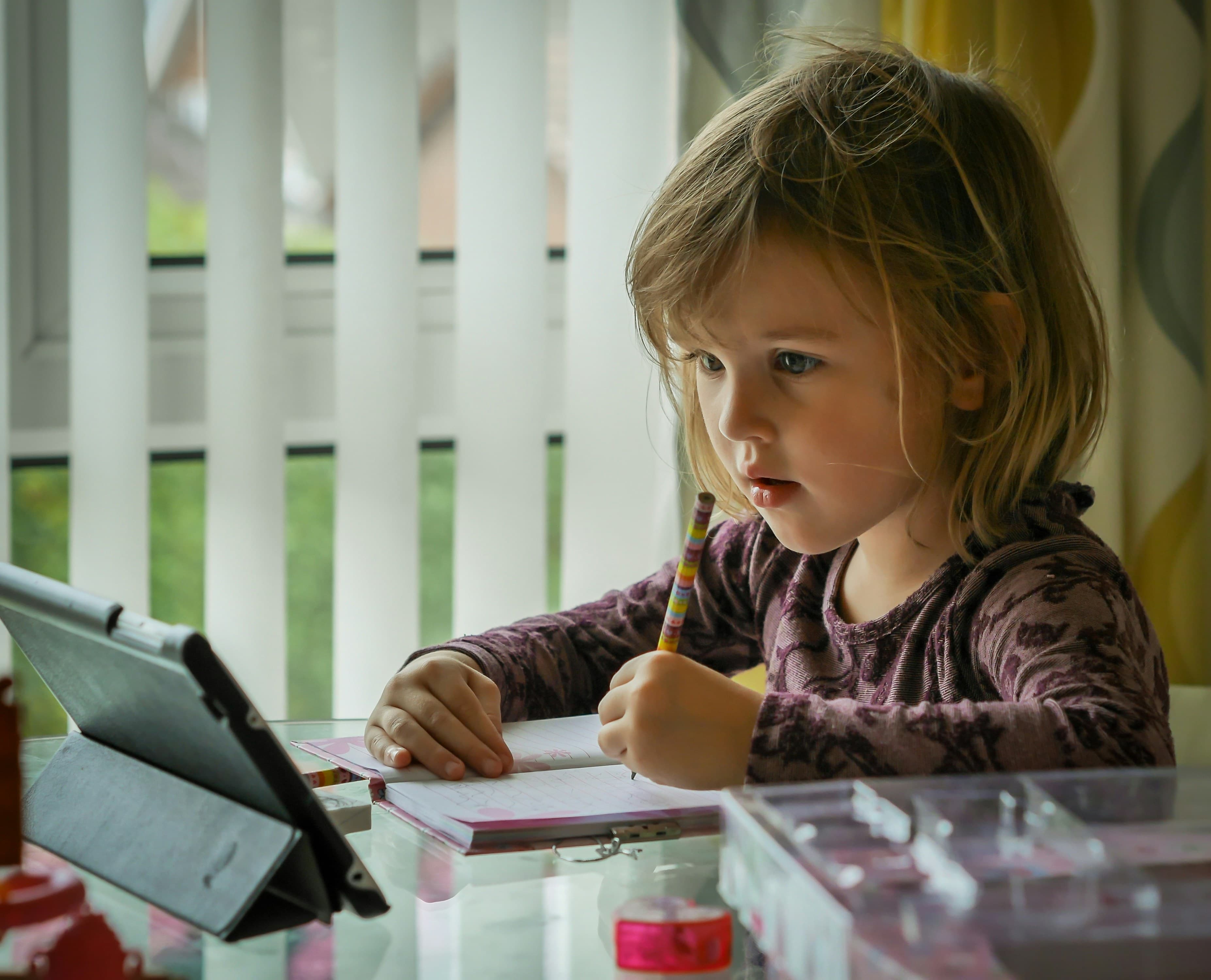 A girl writing on white paper with a black pen