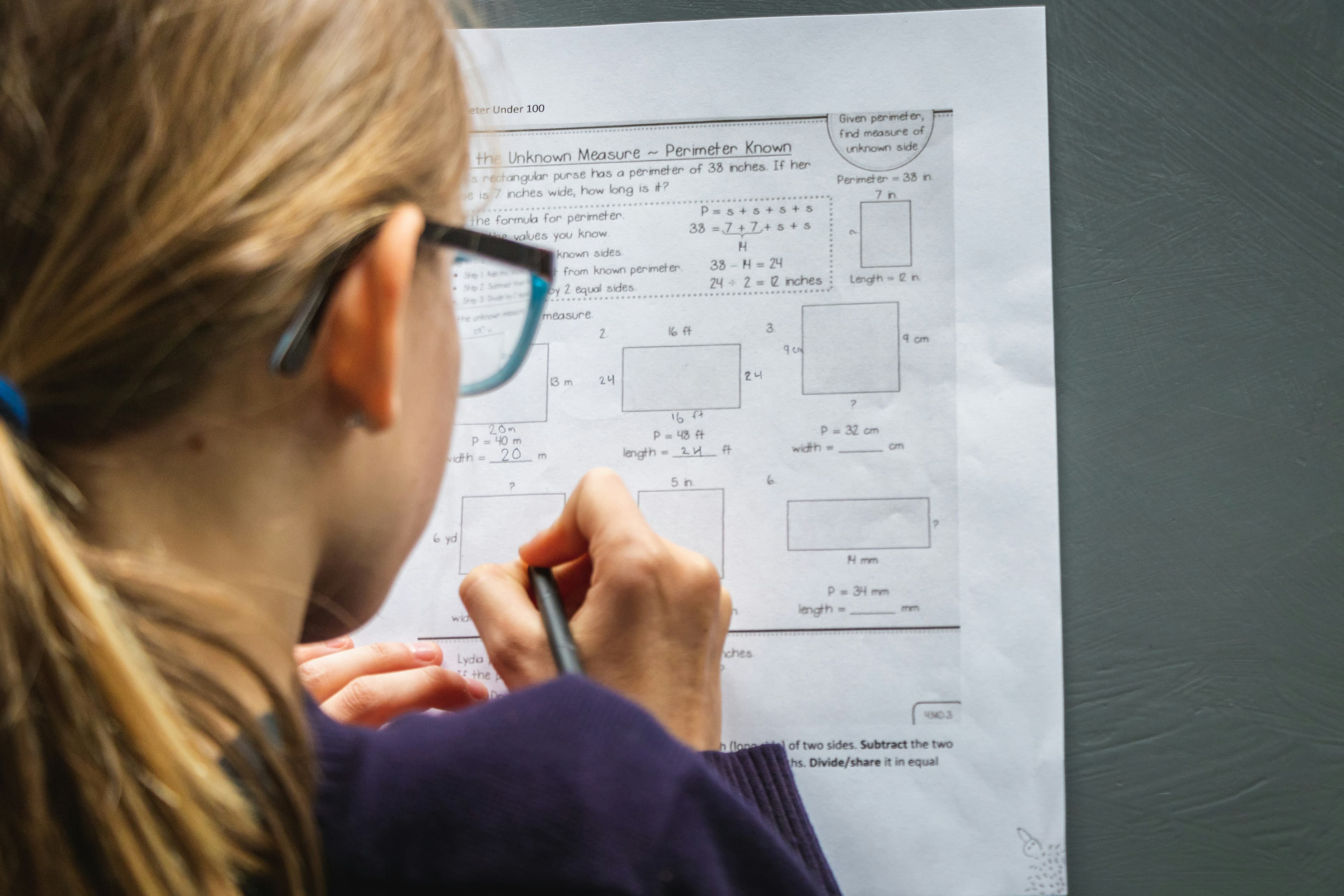 A student in glasses holding a pen while studying