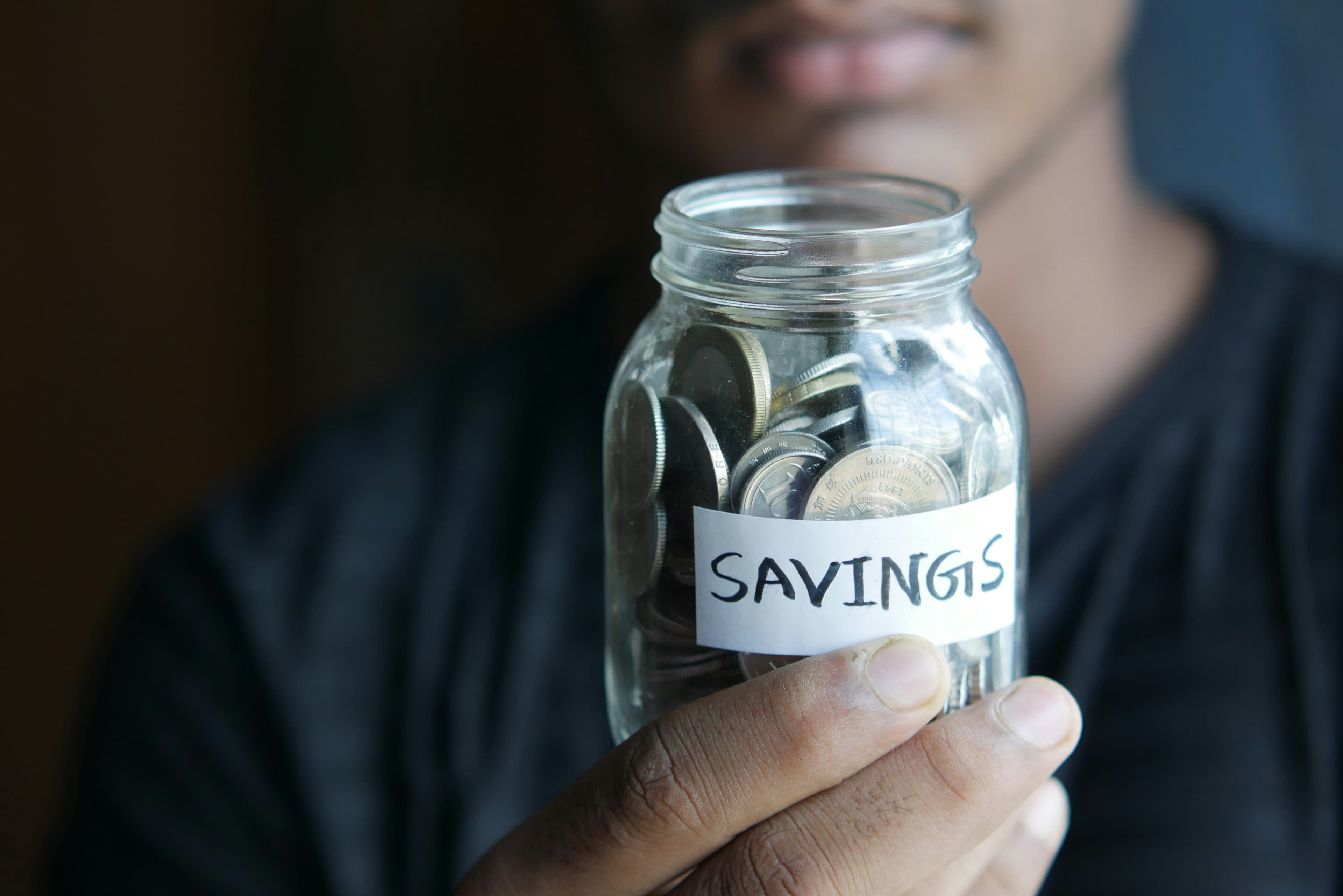 A man holding a jar labeled savings