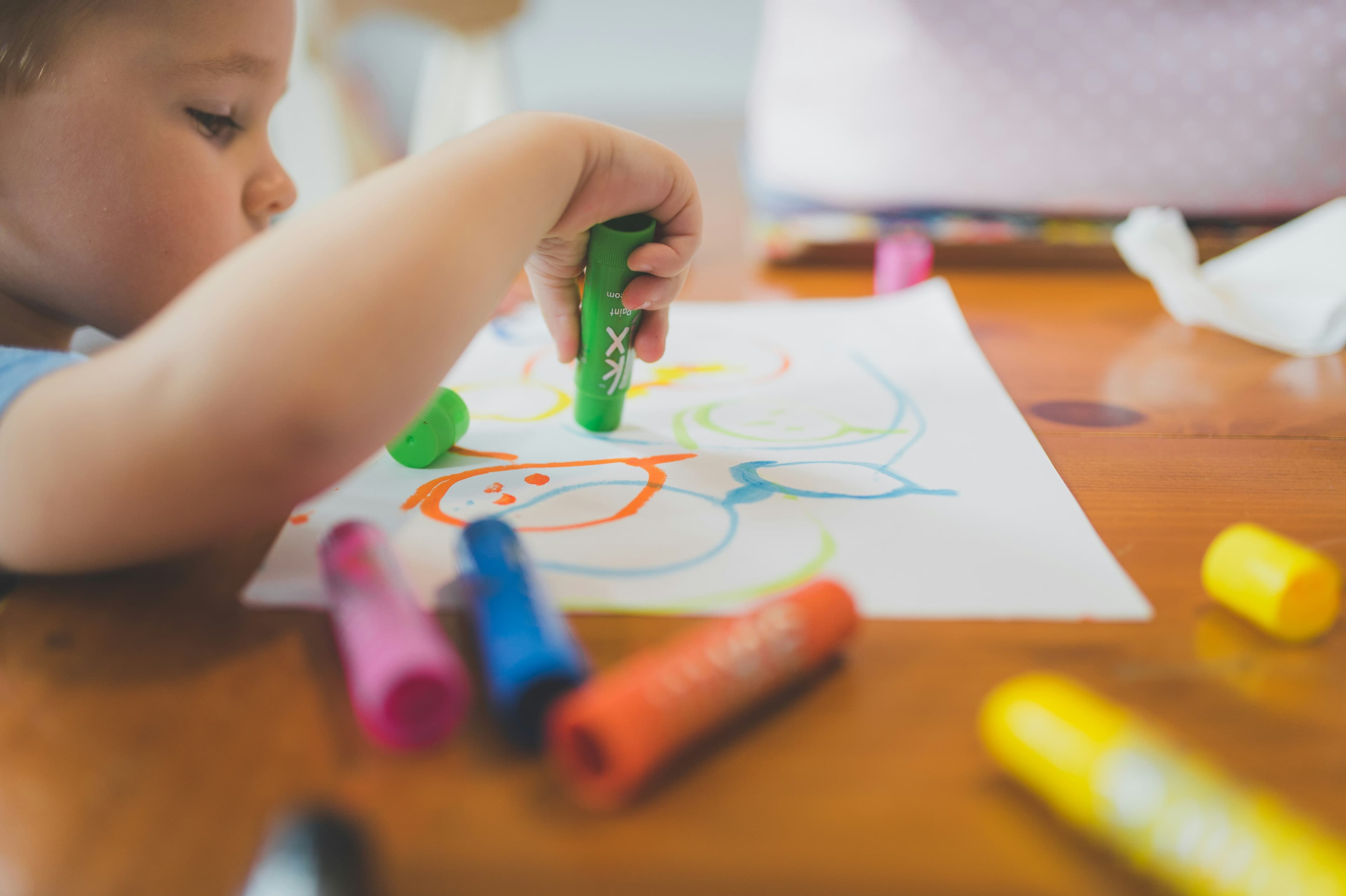 A little boy sitting at a table with crayons