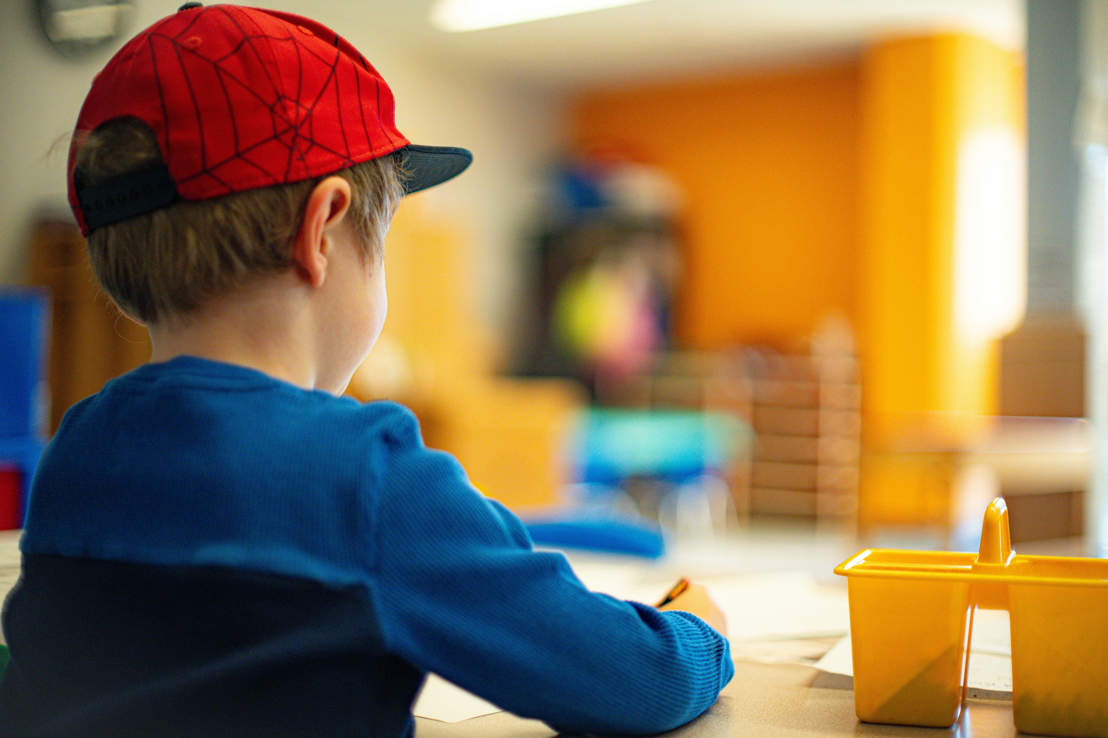 A young boy sitting at a table writing on paper