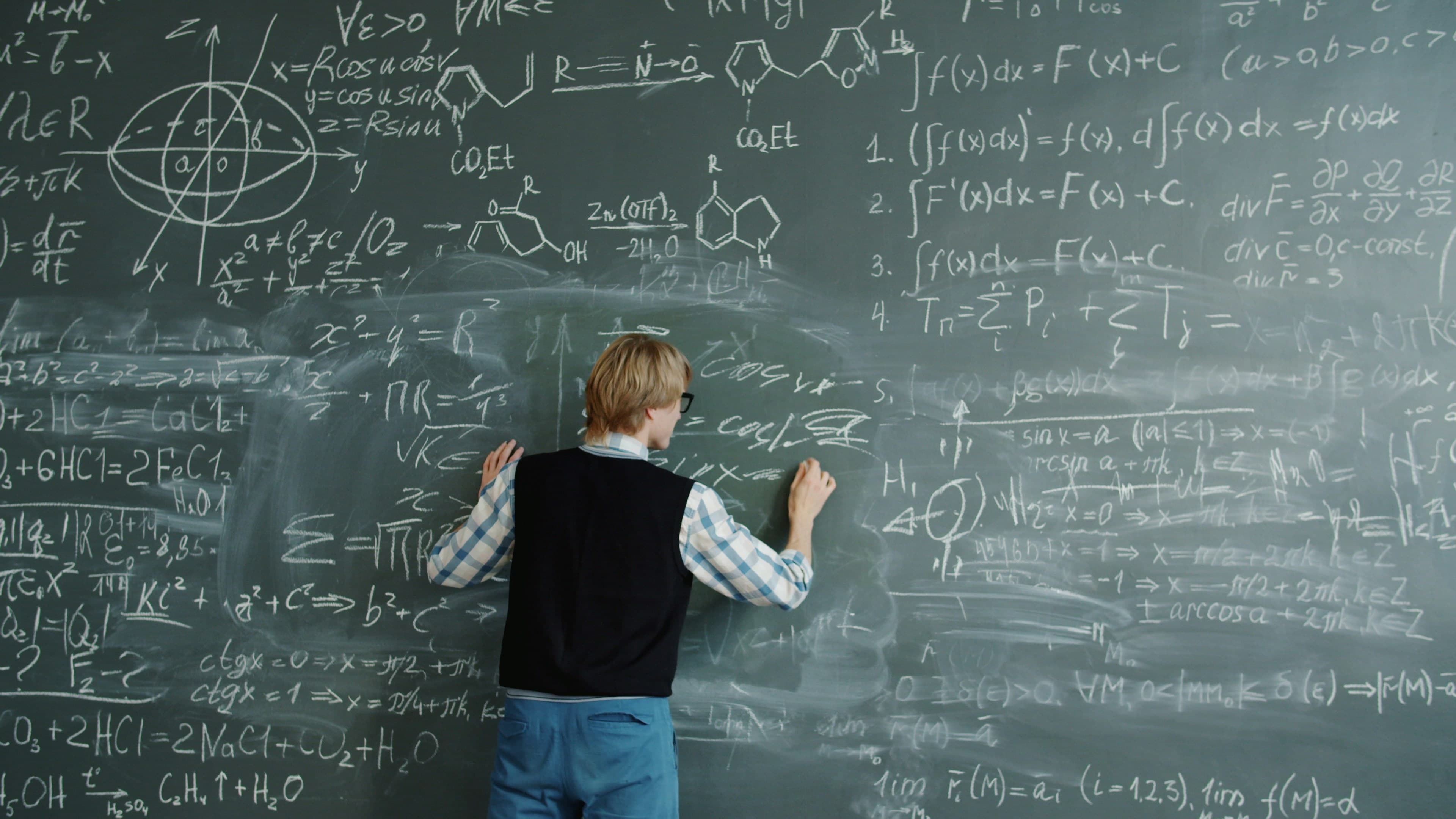 A student writing formulas on a chalkboard